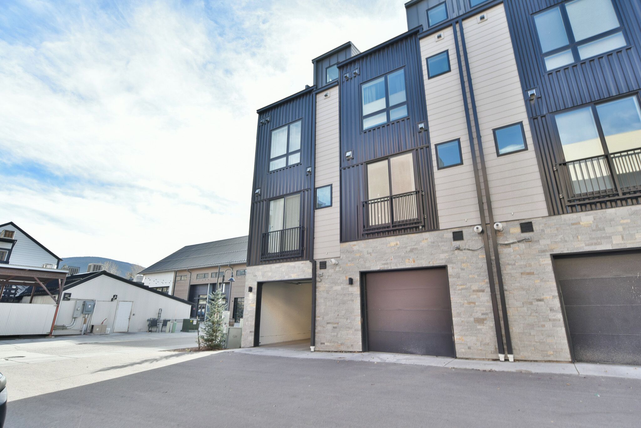 A modern multi-story building with a garage entrance, large windows, and a brick facade.