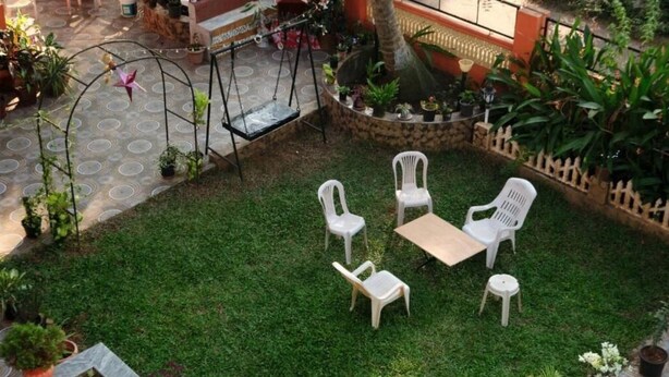 A patio with a swing set, a small table, and four chairs. - Rodrigues Residency (Majorda)