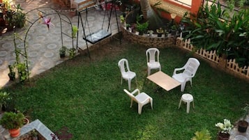 A patio with a swing set, a small table, and four chairs.