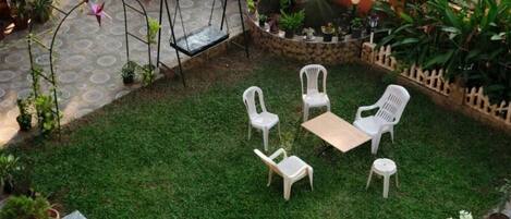 Un patio con un columpio, una mesita y cuatro sillas.