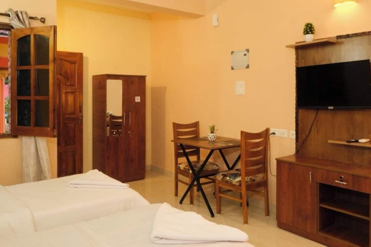 Ein Hotelzimmer mit einem Bett, einem Schreibtisch mit Stühlen, einem Fernseher und einem Schrank.