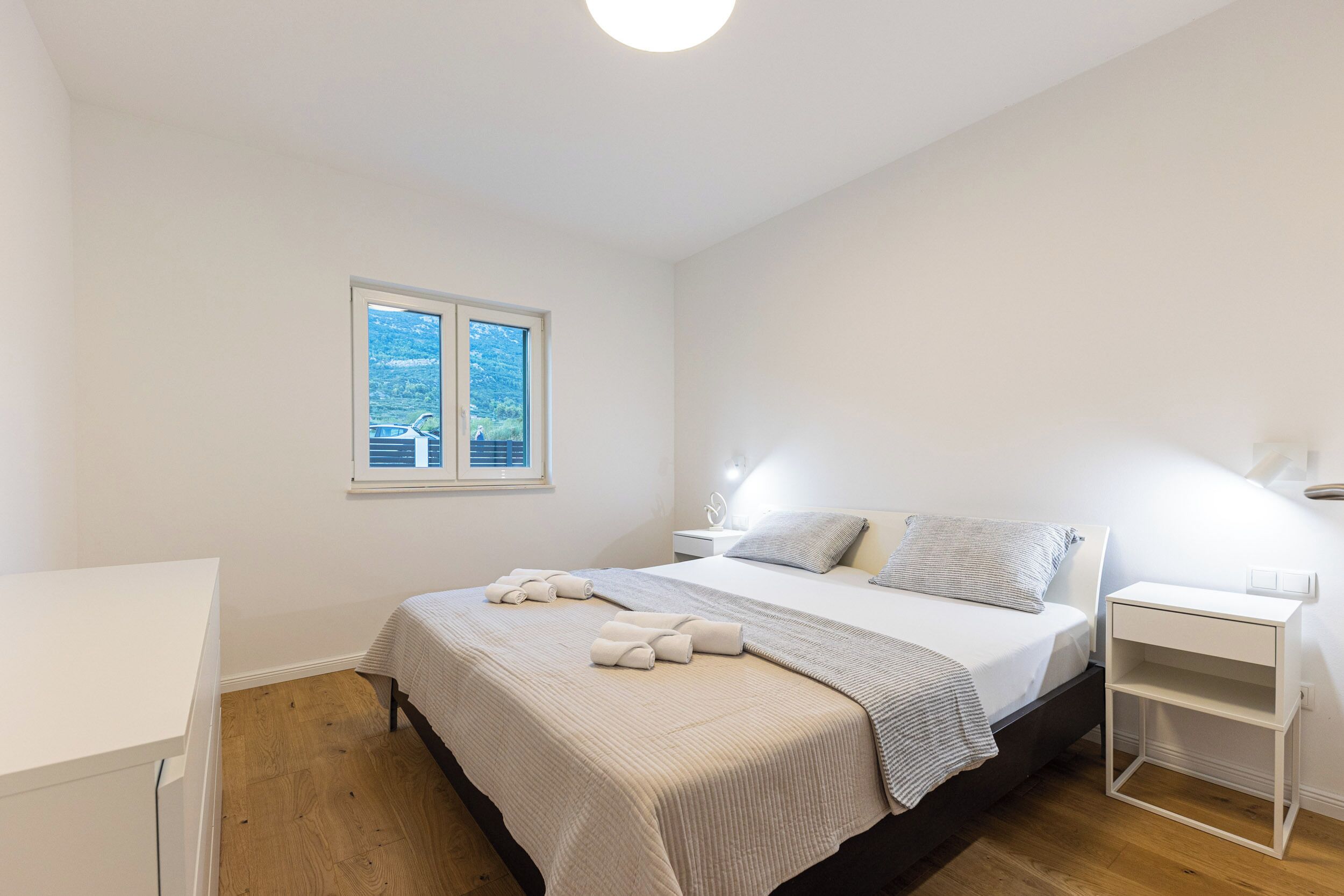 A bedroom with a bed, bedside tables, a window, and a desk.