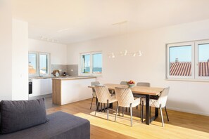 Une cuisine moderne avec des meubles blancs, un îlot central en bois et un coin repas comprenant une table et des chaises.