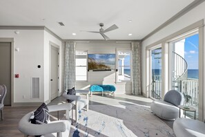 Un salon spacieux doté d’une grande fenêtre, d’un ventilateur de plafond et offrant une vue sur l’océan.