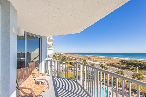 A balcony with a view of the beach and a swimming pool.