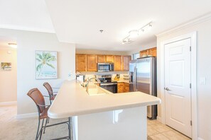 A modern kitchen with wooden cabinets, stainless steel appliances, and a large island with bar stools.