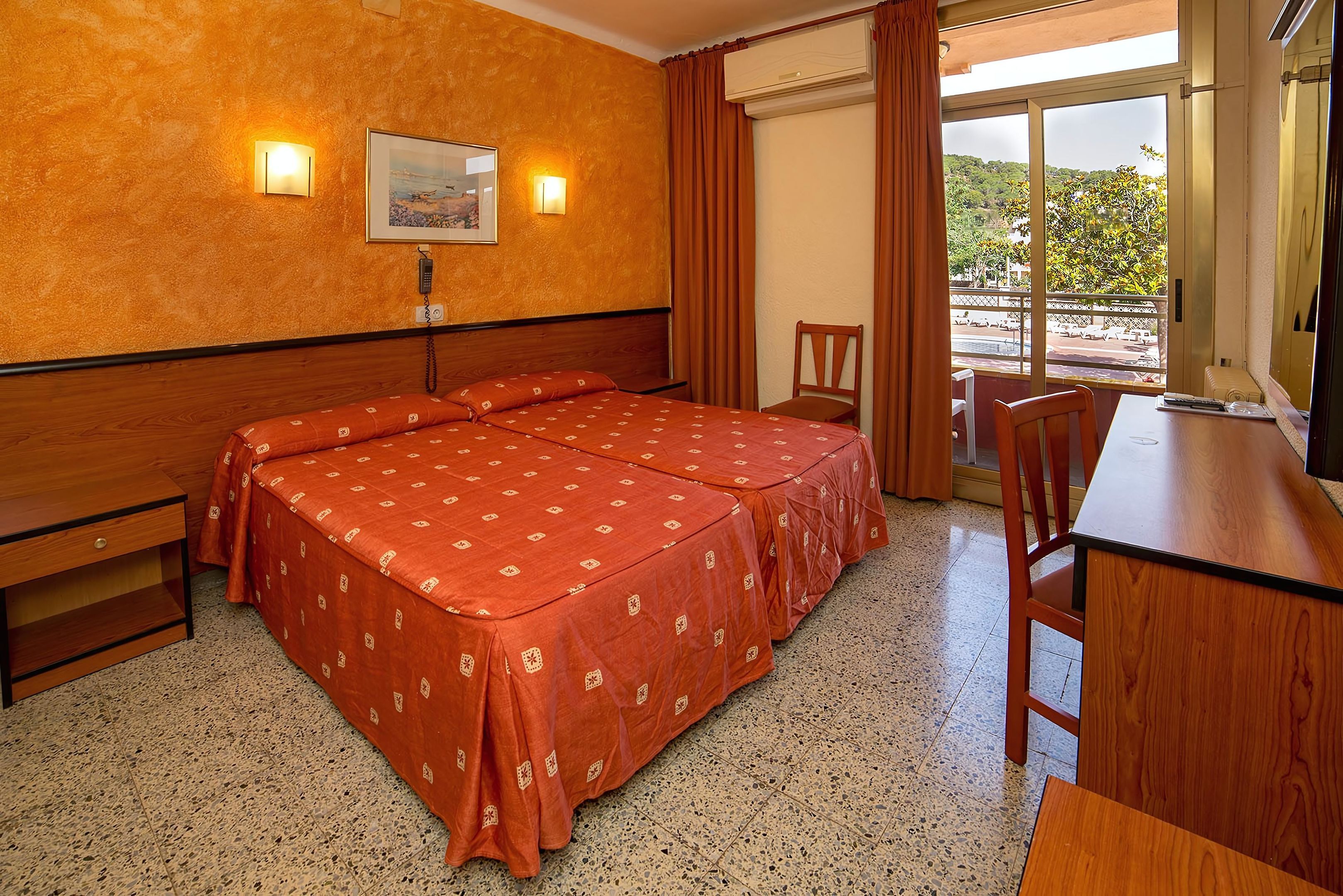 A hotel room with a double bed, a desk, and a chair.