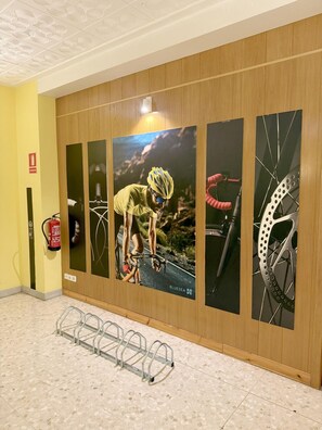 A hallway with wooden paneling, a fire extinguisher, a bike rack, and a series of framed images on the wall. - BLUESEA Continental (Tossa de Mar)
