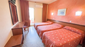 A hotel room with two beds, a desk, a chair, an air conditioning unit, and a window with curtains. - BLUESEA Continental (Tossa de Mar)