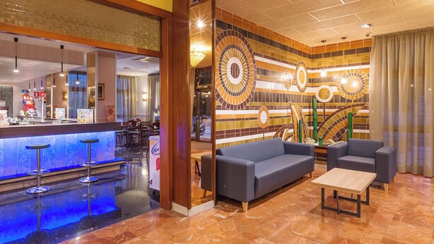 A modern lobby with a bar area, seating, and a decorative wall. - BLUESEA Continental (Tossa de Mar)