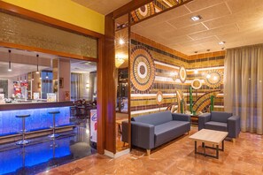 A hotel lobby with a bar area, seating, and a decorative wall with circular patterns. - BLUESEA Continental (Tossa de Mar)