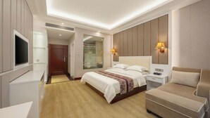 A modern hotel room with a large bed, bedside tables, a TV, and a seating area.
