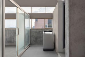 A narrow corridor with a sliding glass door leading to a balcony, a small kitchenette, and a view of buildings in the distance. - Hengxian Longxiang Crown Hotel (Hengzhou)