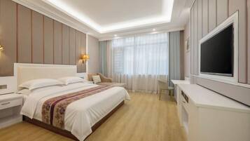 A hotel room with a large bed, bedside tables, a TV, and a desk.