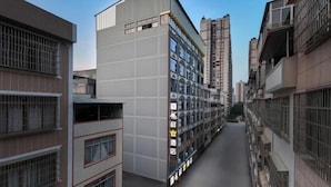 Une rue étroite en milieu urbain, bordée d’immeubles à plusieurs étages dotés de balcons et de fenêtres.