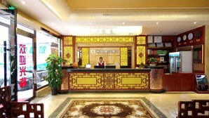 A hotel reception area with a traditional design, featuring a reception desk, a large decorative rug, and a clock on the wall.