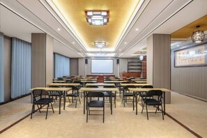 A conference room with tables and chairs arranged for meetings, a large screen at the front, and a ceiling with recessed lighting. - Hengxian Longxiang Crown Hotel (Hengzhou)