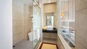 A modern bathroom with a glass shower enclosure, a toilet, and a sink with a mirror above it.