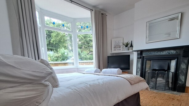 Quarto com cama grande, lareira e janela com cortinas.