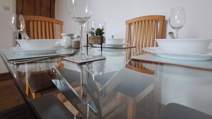Uma mesa de jantar com cadeiras, copos de vidro transparentes e uma pequena planta.