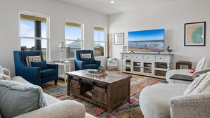 Un amplio salón con un ventanal grande, una mesa de centro de madera y un televisor sobre un mueble blanco.