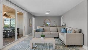Ein Wohnzimmer mit einem beigefarbenen Ecksofa, einem Couchtisch und einem Teppich mit Muster.