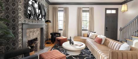 A living room with a fireplace, a sofa, a coffee table, and a staircase.