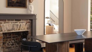 A modern dining area with a stone fireplace, a large mirror, and a chandelier.