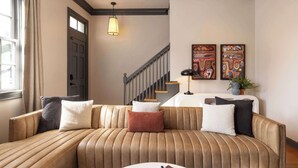 A modern living room with a leather sofa, a coffee table, and two abstract paintings on the wall.