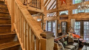 L’intérieur d’une cabine, avec un escalier en bois, un ensemble de canapés et un lustre.