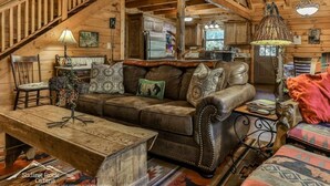 L’intérieur d’une cabane comprend un escalier en bois, un canapé en cuir, une table à manger et un coin cuisine.