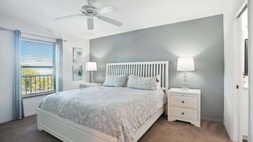 A bedroom with a bed, bedside tables, a ceiling fan, and a window with blinds.