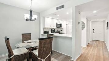 A modern kitchen with white cabinets, a microwave, and a coffee maker.