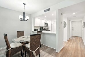 A modern kitchen with white cabinets, a microwave, and a coffee maker.