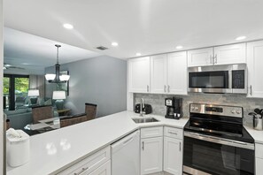 Una cocina moderna con gabinetes blancos, electrodomésticos de acero inoxidable y una isla grande.