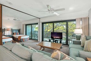 A spacious living area with a sofa, a coffee table, and a TV on a balcony.