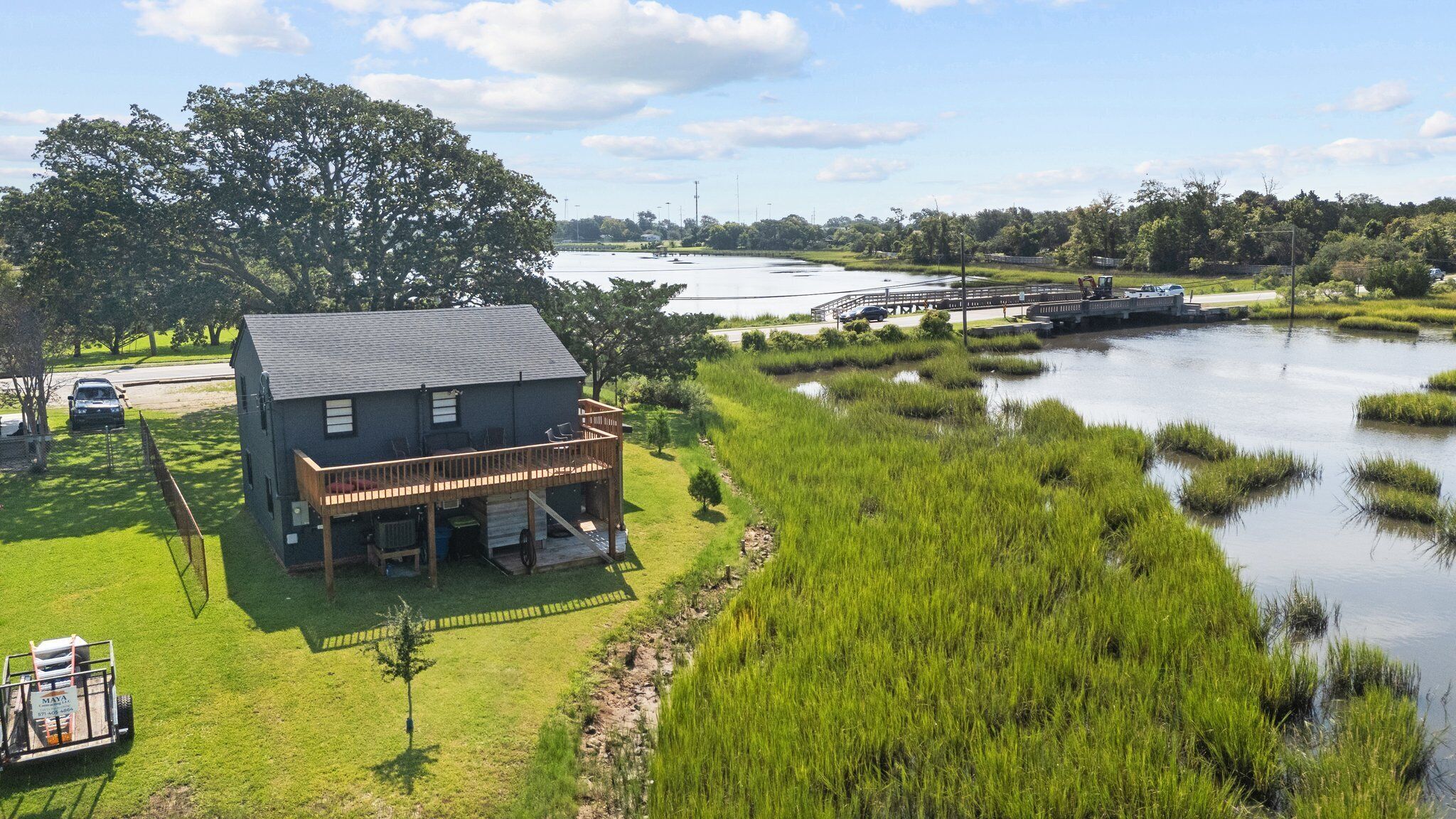 Ein Haus mit Terrasse, das auf einen Fluss blickt, umgeben von üppiger Vegetation und einem kleinen Steg.