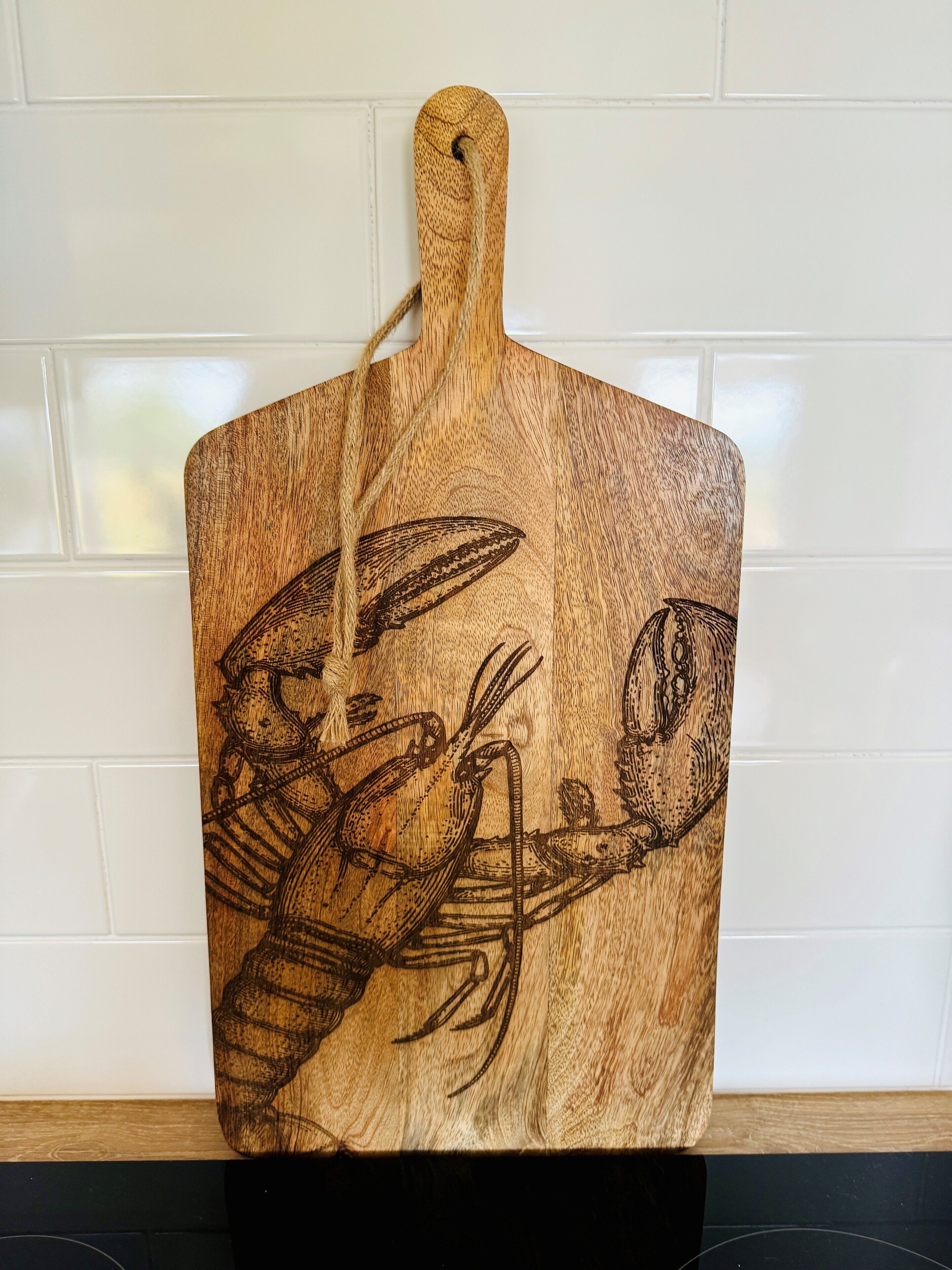 A wooden cutting board with a lobster design.