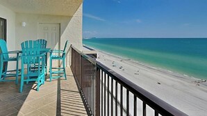 A balcony with turquoise chairs overlooking a beach with clear turquoise water and a sandy shore. - Ocean Sands 1-1002☀️Beachfront,Private Balcony,Walk 2 Restaurants🏖️Beach Access (Madeira Beach)
