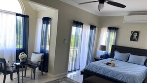 A bedroom with a bed, a desk, chairs, and a view of the outdoors. - Charming 2-bedroom townhome with WiFi, AC in beautiful Ocho Rios (Ocho Rios)