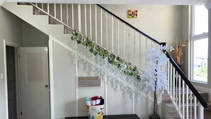 A staircase with white railings, a bench with a basket of items, and a hanging floral arrangement. - Charming 2-bedroom townhome with WiFi, AC in beautiful Ocho Rios (Ocho Rios)