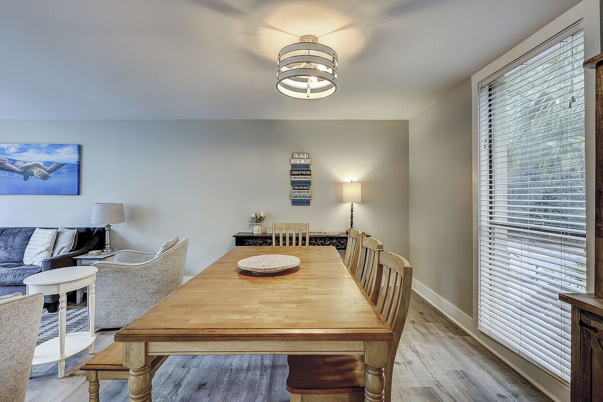 Un comedor con mesa de madera, sillas, candelabro y un cartel en la pared.