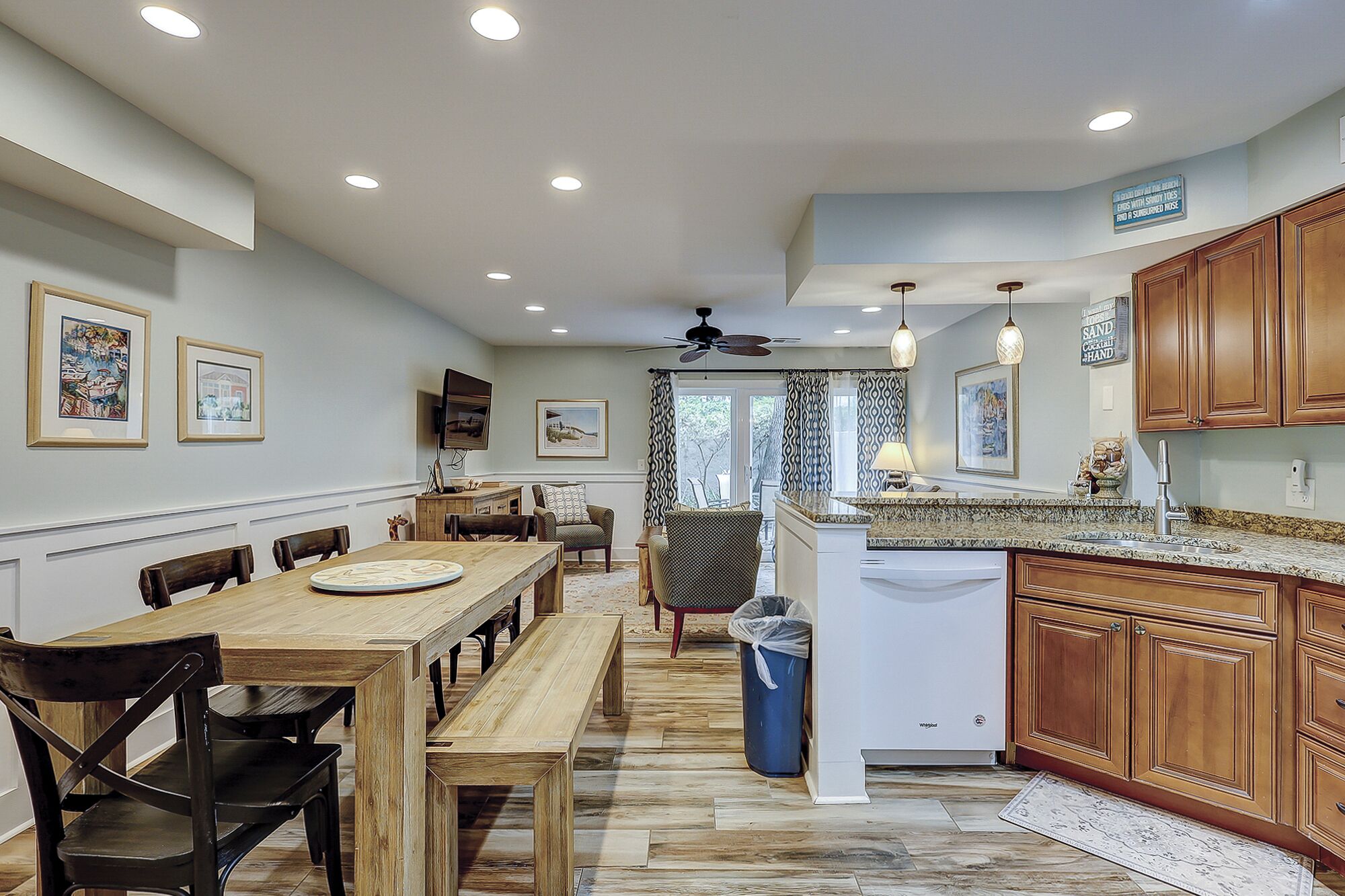 A spacious kitchen with wooden cabinets, a dining area with a large wooden table, and a ceiling fan.