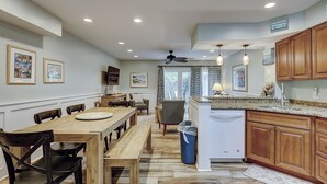 A spacious kitchen with wooden cabinets, a dining area with a large wooden table, and a ceiling fan. - Sunset Rentals | Continental Club 1 (Hilton Head Island)