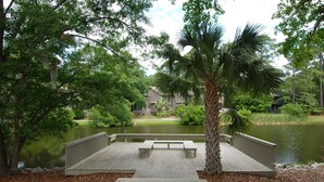 A wooden dock with benches, a palm tree, and a body of water. - Sunset Rentals | Ocean Cove 826 (Hilton Head Island)