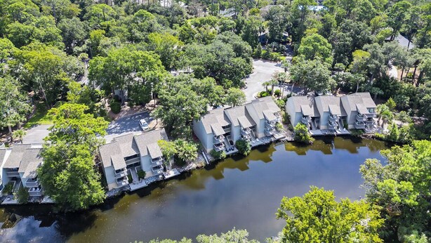 A coastal hotel with multiple buildings along a water body, surrounded by dense greenery. - Sunset Rentals | Ocean Cove 826 (Hilton Head Island)