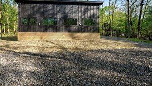 Eine moderne Holzblockhütte mit Kiesweg, umgeben von Bäumen.