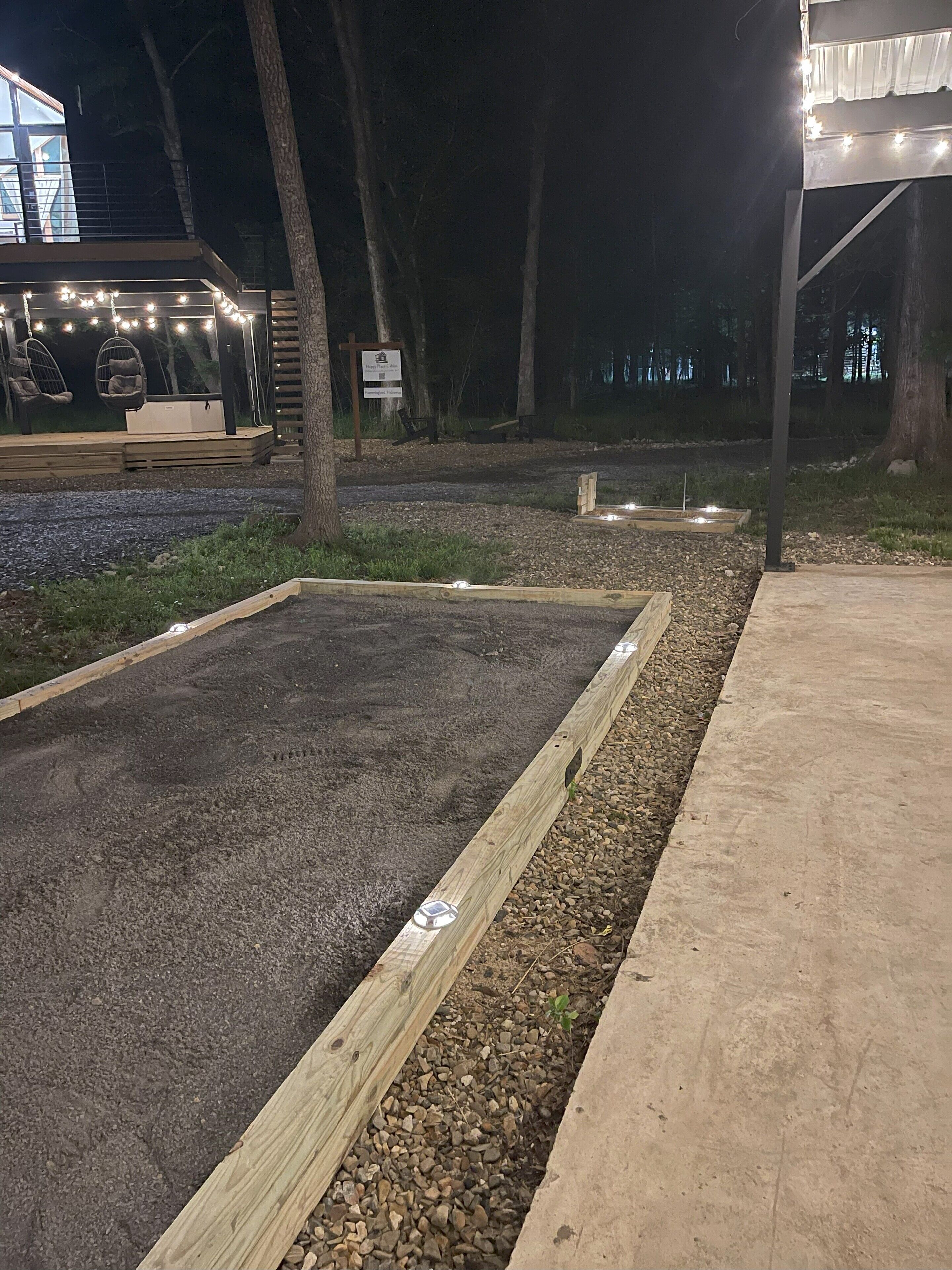 A garden area with raised beds, a wooden deck, and string lights.