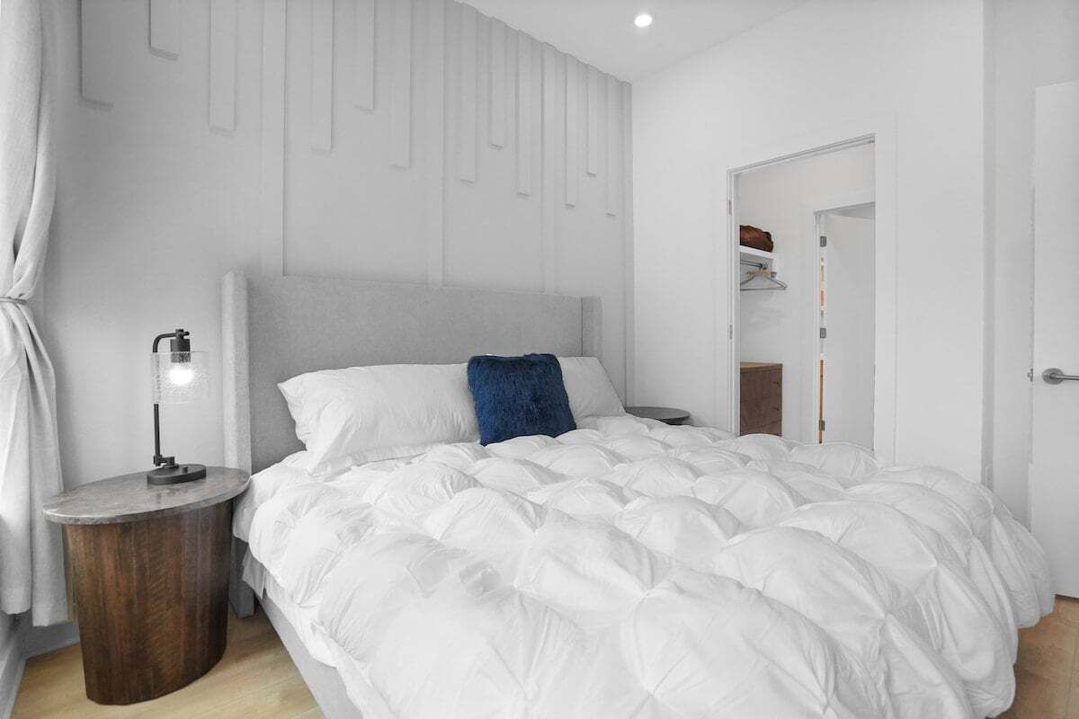 A bedroom with a large bed, a bedside table with a lamp, and a wardrobe.