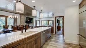 Una cocina moderna con una isla grande, armarios de madera e iluminación colgante.